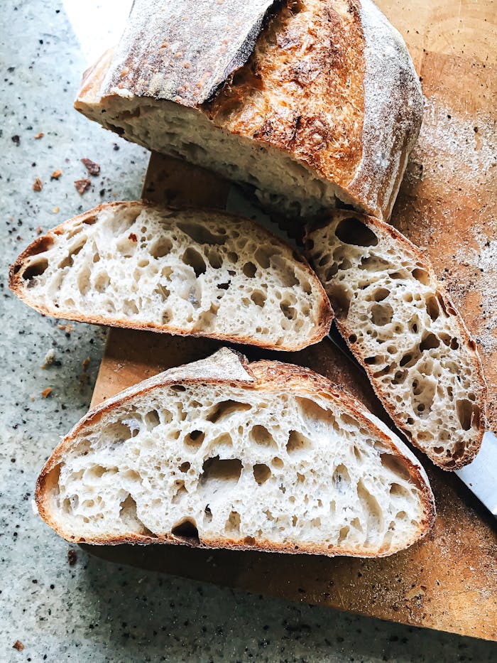 Freshly baked sourdough bread with airy crumb, sliced on a cutting board. Perfect for breakfast or snack.